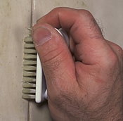 Cleaing grout using a small brush.